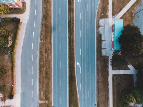 Aerial view of divided suburban roadway with marked lanes and sidewalks