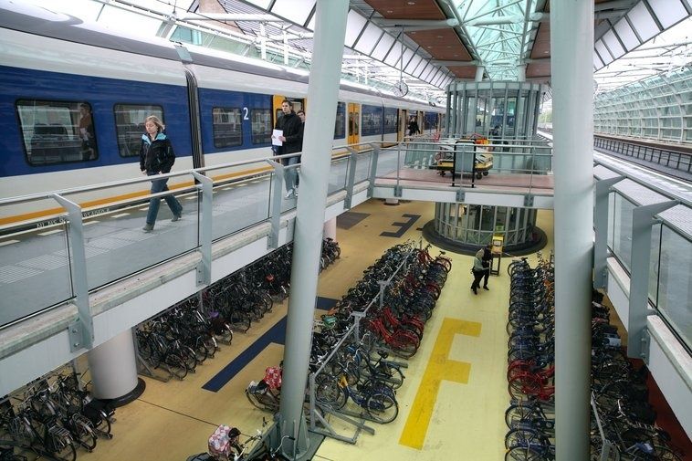 Commuter train beside a station packed with bicycle racks