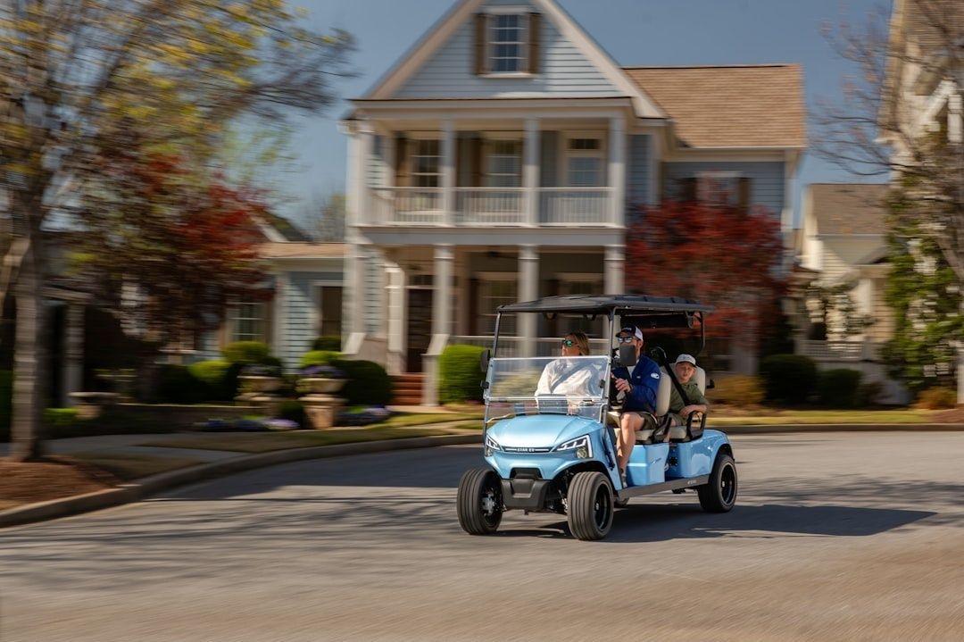 Open electric shuttle carrying passengers through a suburban neighborhood